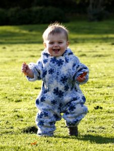 A smiling baby standing in a field